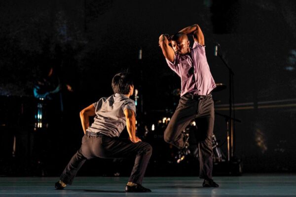 A man crouches, another looms over him