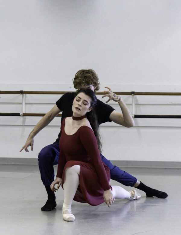 A male dancer behind female dancer in red