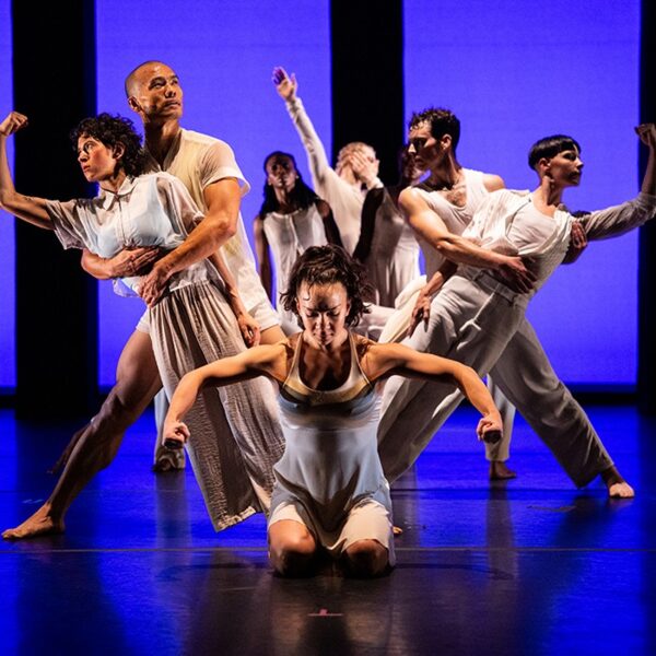 Dancers in white lean in different directions