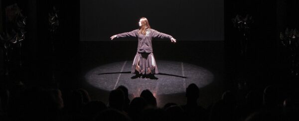 A dancer holds out her arms before an audience