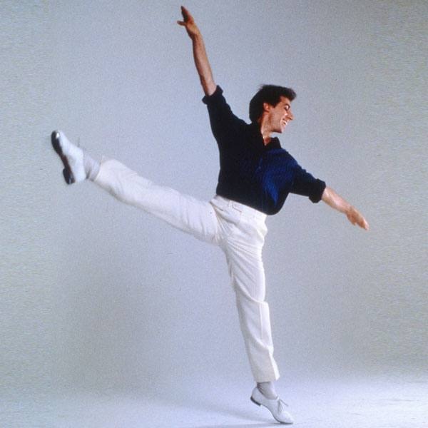 A tap dancer in white pants kicks his leg