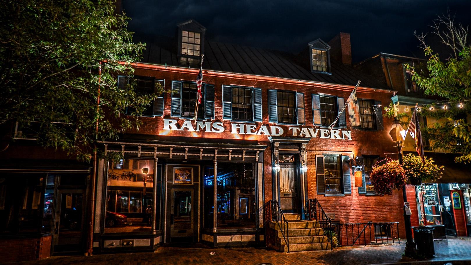 Rams Head Tavern brick exterior lit up at night with string lights and hanging flowers