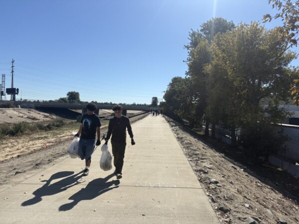 two students carrying trash at Compton Creek