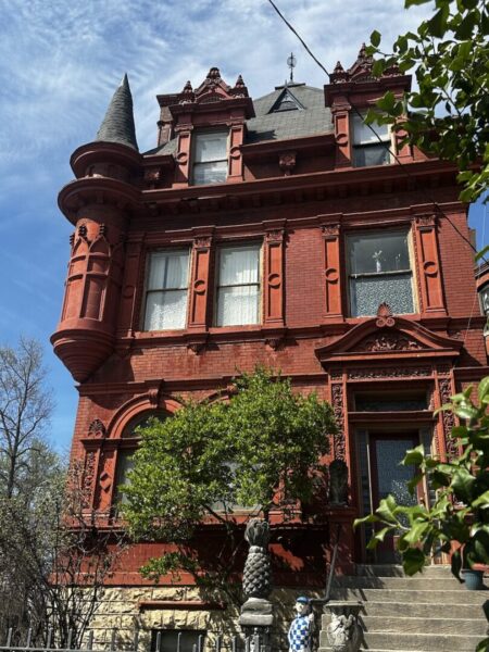A red stone Victorian home in Old Louisville with a corner turret. 