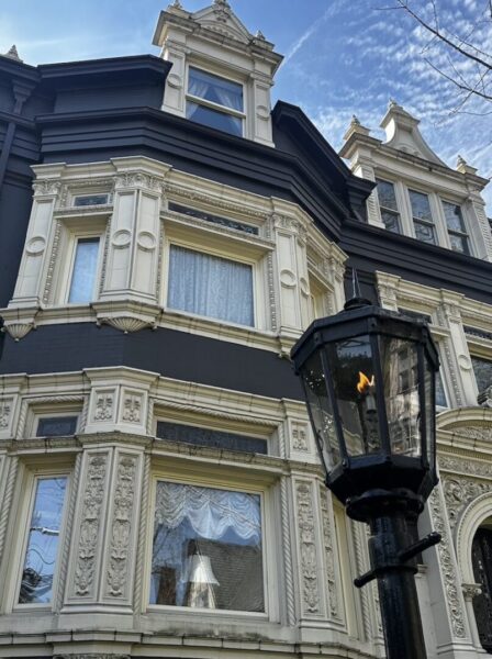 A large Victorian mansion with a gas-lit lamp in front of it. 