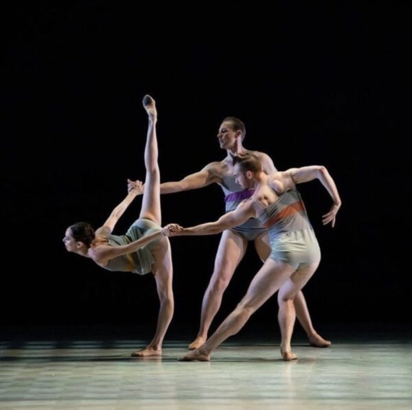 Two male dancers support a female dancer in arabesque