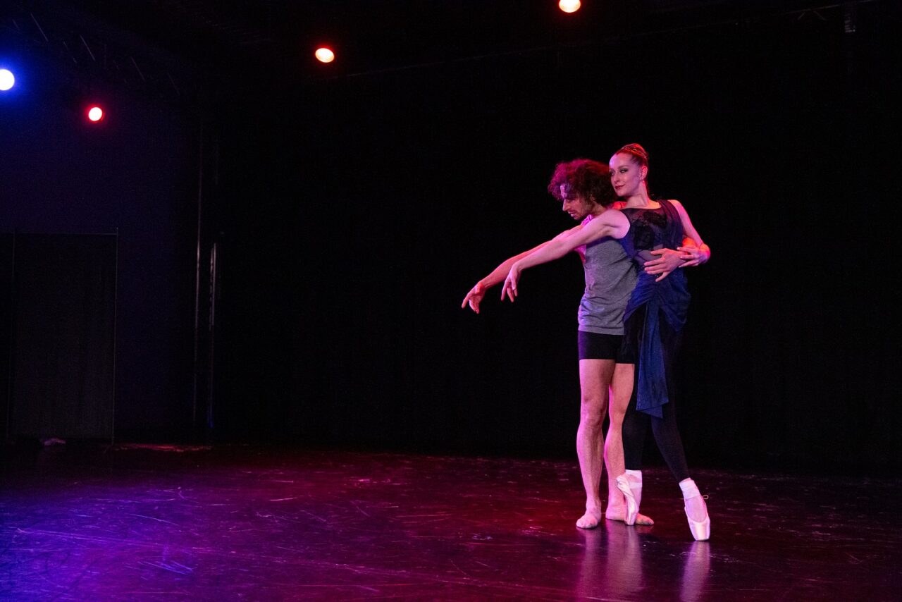 A female dancer leans against a male dancer