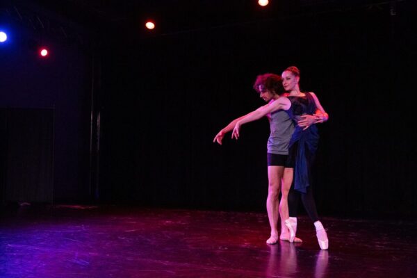 A female dancer leans against a male dancer
