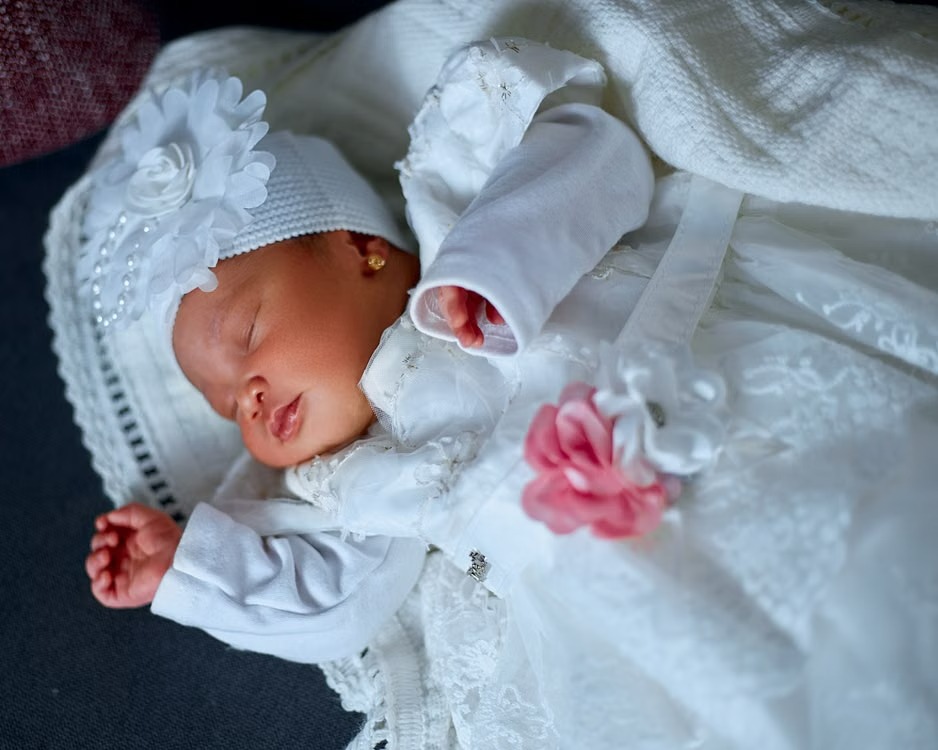 CD-Insert1 Sleeping newborn in white lace outfit and floral knit hat with a pink flower accent