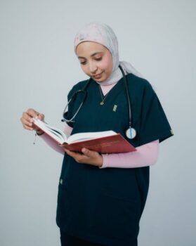 CD-nursing-shortage-texas-Insert1 Young woman in a white coat reading a thick medical book at a desk