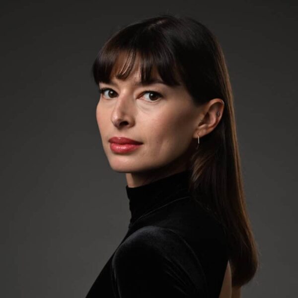 A brunette with bangs looks at camera