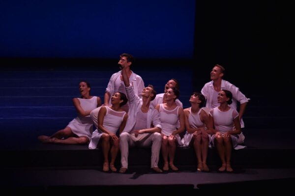 A seated group of dancers look up