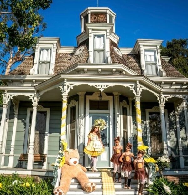 Dancers pose in front of ornate house