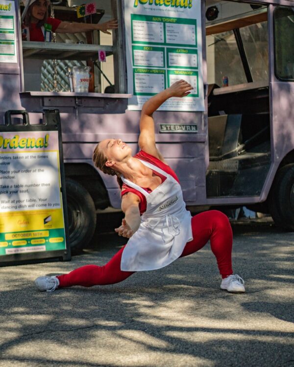 A dancer lunges in front of food cart
