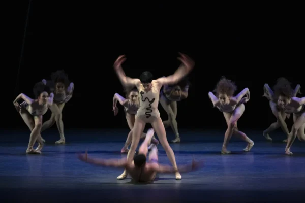 A dancer stands over another dancer on the ground