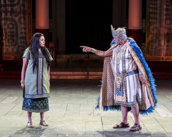 A man in royal robe points his figure at a woman