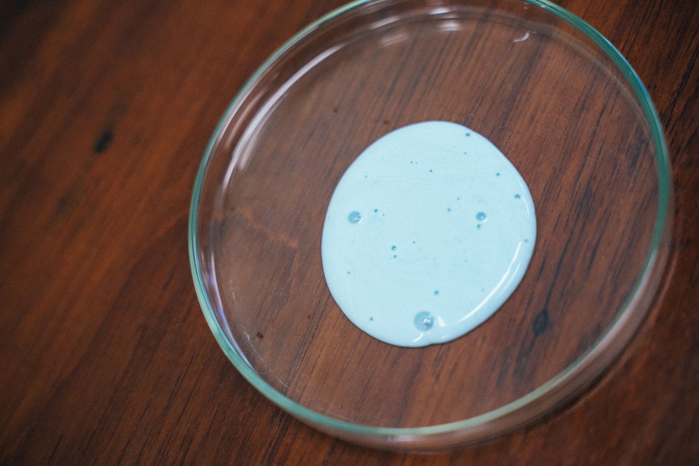 CD-healthcare-virtual-assistant-Insert3 Close-up of blue liquid in a petri dish on a wooden surface