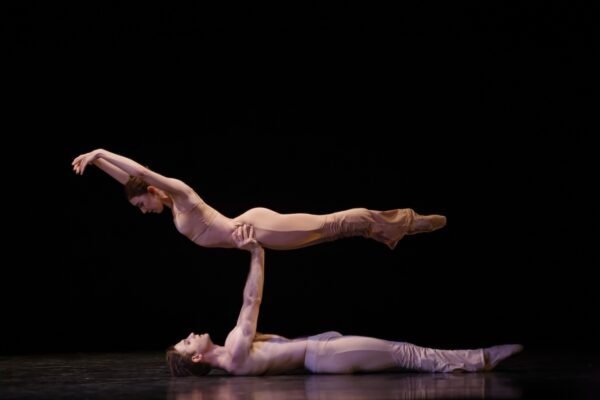 A man on the ground lifts a female dancer