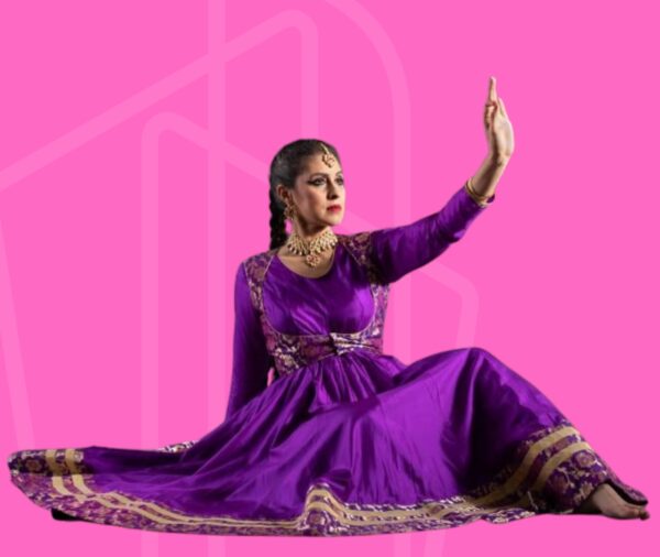 A South Asian dancer in purple raises her hand