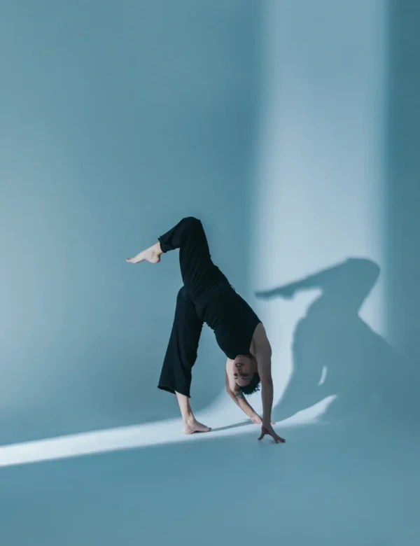A dancer in black costume lifts one leg