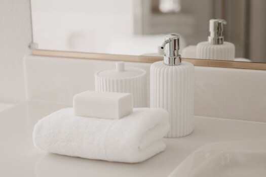 CD-Insert1 Folded white towel and soap on a white bathroom vanity in morning light