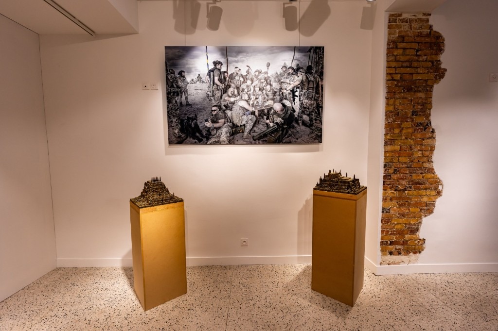 CD-Insert2 Black-and-white photograph of soldiers above two gold pedestals with miniature buildings, next to exposed brick