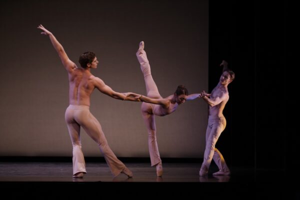 Two male dancers hold female dancer in arabesque